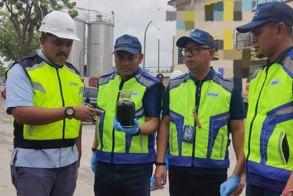 Mohd Fazil (kiri) dan pegawainya menunjukkan sampel air yang diambil untuk dihantar ke Jabatan Kimia untuk tindakan lanjut.