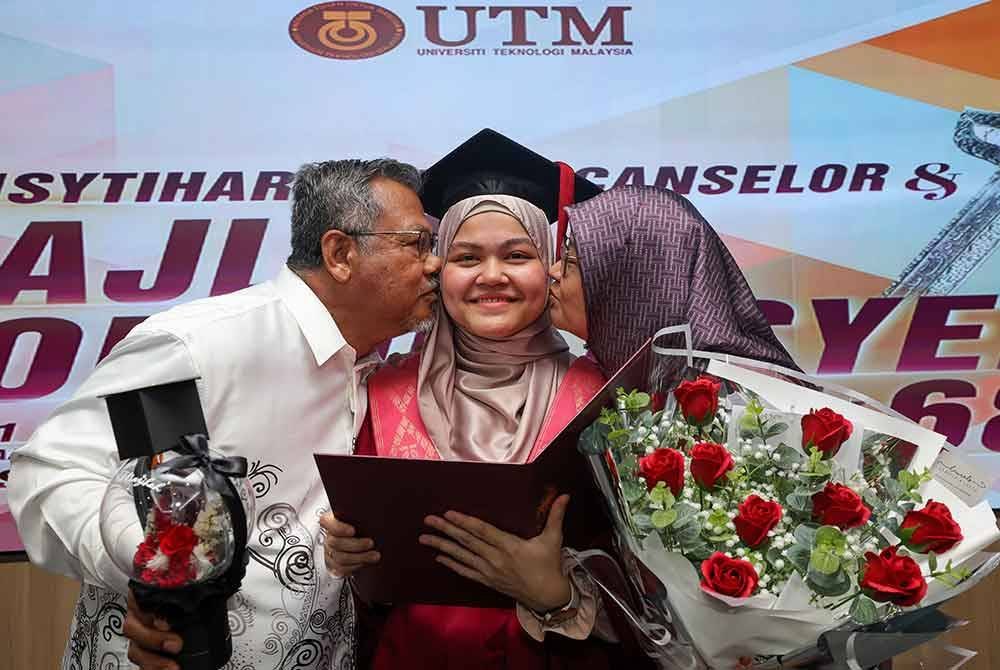 Nazihah menerima ciuman daripada ibu bapanya, Surati Abdul Rahman (kiri), 62, dan Hamisah Mohd Ariff, 54, pada Majlis Konvokesyen Ke-68 Universiti Teknologi Malaysia (UTM), di UTM Skudai, pada Selasa. Foto Bernama