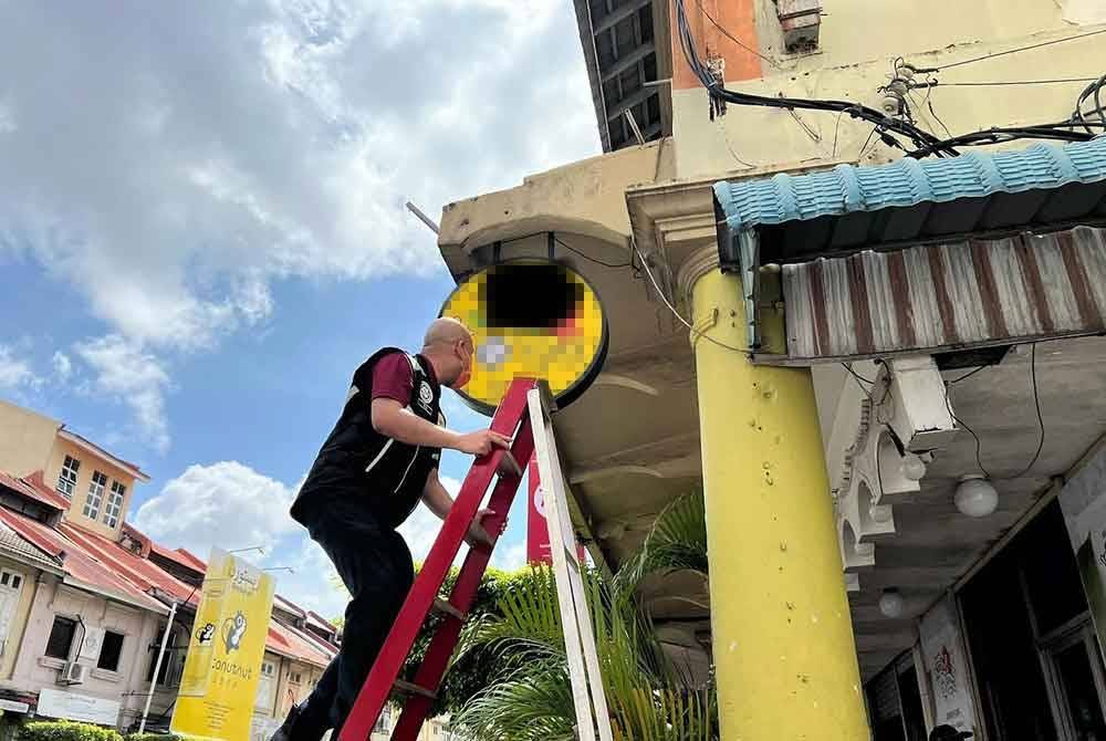 enguat kuasa KPDN dan JAHEAIK menurunkan papan tanda dan kain rentang restoran yang menggunakan logo halal tak sah dalam serbuan tengah hari semalam. Foto KPDN