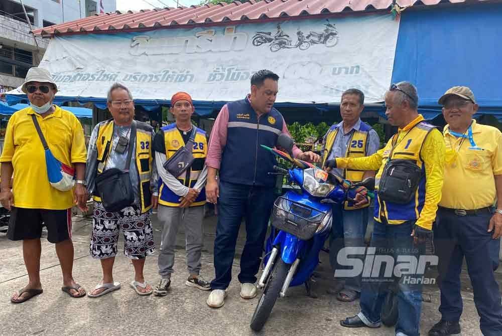 Amin (tengah) bertanyakan khabar kepada pekerja motosikal penambang yang mengeluh tidak dapat mencari rezeki selepas ramai rakyat Malaysia tidak datang ke Pekan Golok, Thailand.