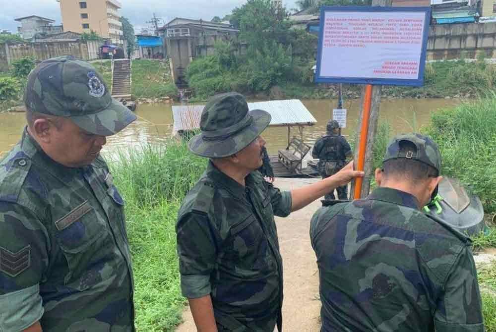 Beberapa anggota PGA memasang papan tanda amaran di tebing Sungai Golok. Foto Bernama