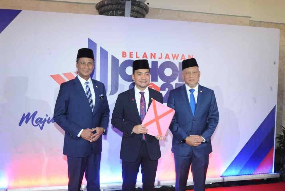 Onn Hafiz (tengah) menunjukkan Buku Belanjawan Johor 2025 Bangunan Sultan Ismail Kota Iskandar, Iskandar Puteri pada Khamis.