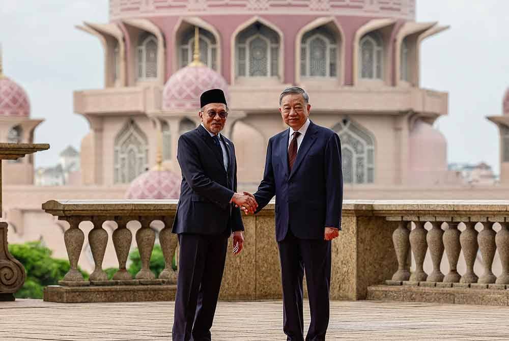 Anwar (kiri) menyambut To Lam yang dalam lawatan tiga hari ke Malaysia. Foto Bernama