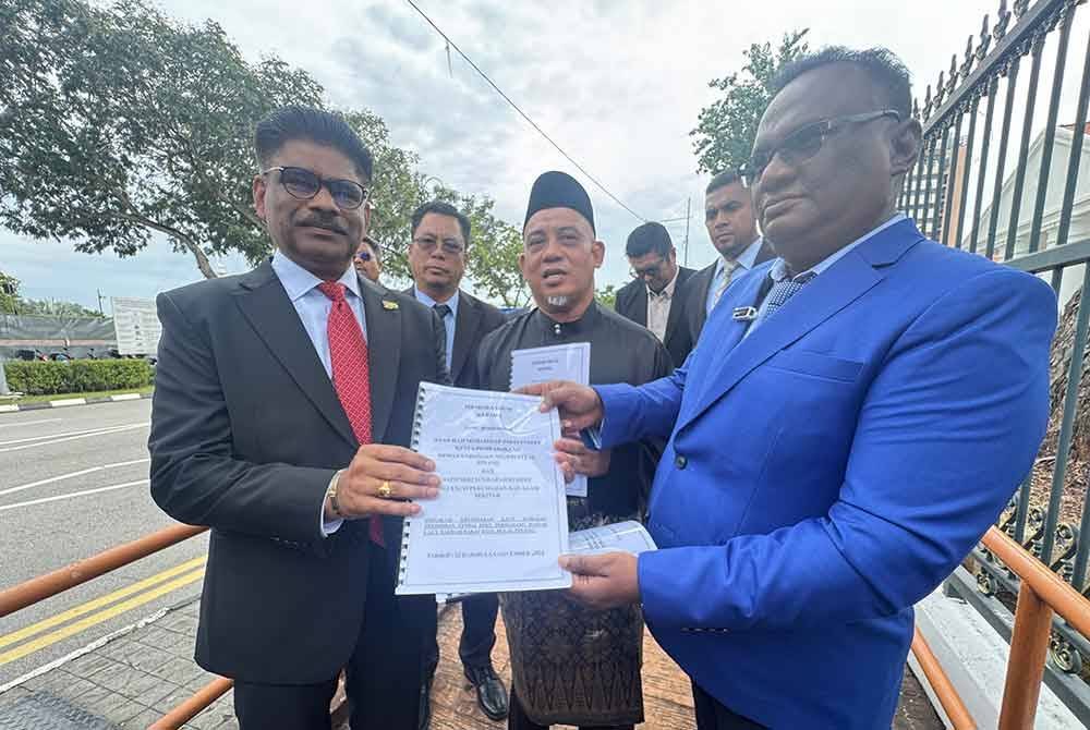 Annathurai (kanan) menyerahkan memorandum kepada Muhammad Fauzi (tengah) dan Sundarajoo (kiri) di luar pekarangan bangunan DUN Pulau Pinang pada Jumaat.