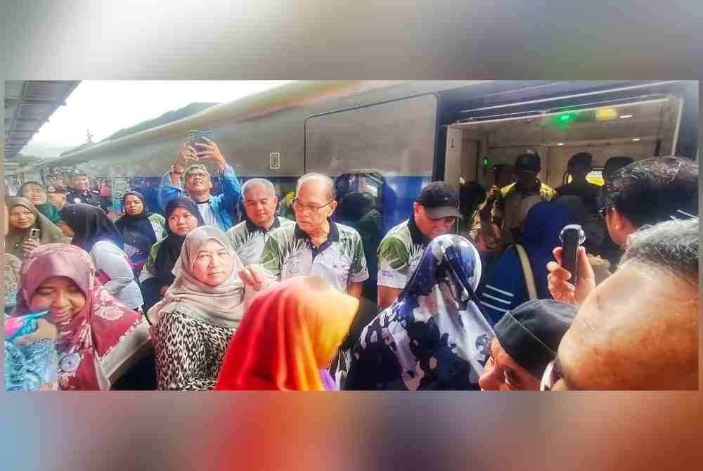 Wan Rosdy (tengah) menyantuni penumpang yang menaiki gerabak keretapi sempena perasmian program itu di Stesen Keretapi Kuala Lipis pada Jumaat.