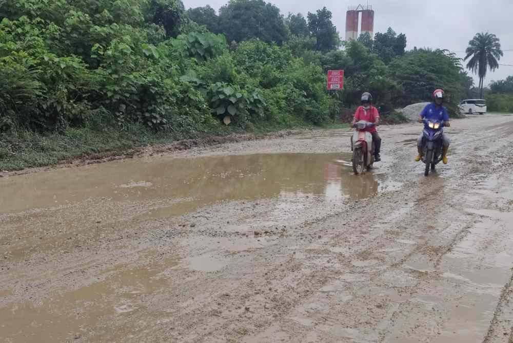 Penunggang motosikal terpaksa berhati-hati melalui jalan licin, berlopak di Jalan Pasar Malam di Kampung Bukit Kapar di sini.