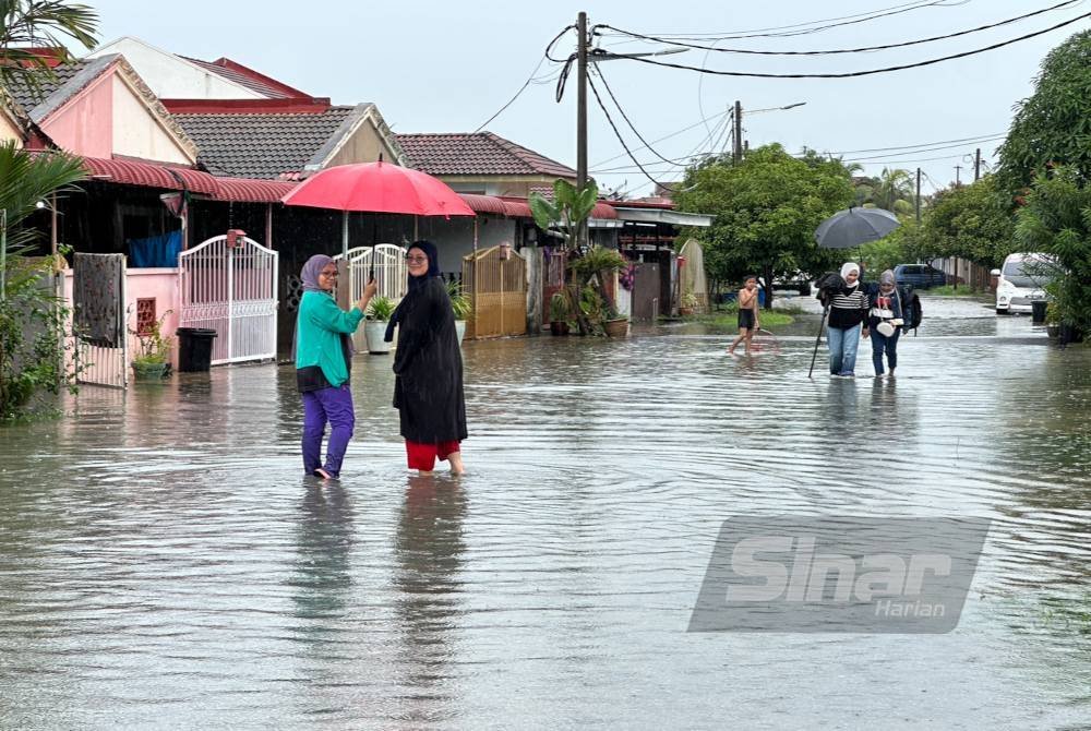 Penduduk terpaksa meredah banjir untuk pulang ke rumah masing-masing. Foto Sinar Harian ADILA SHARINNI WAHID