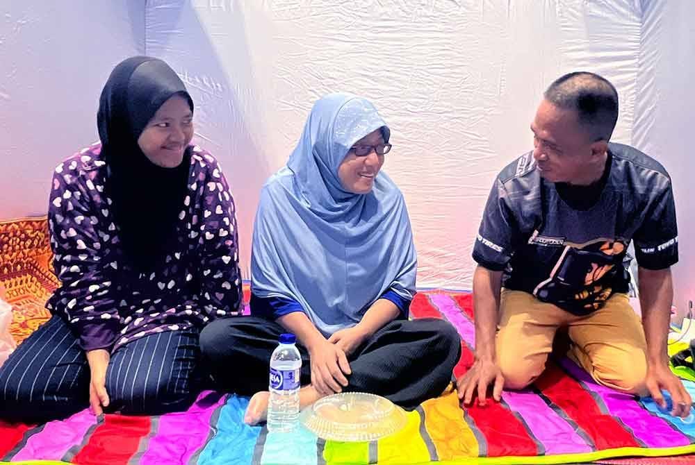 Mangsa banjir, Mazlina Mohamed, 45 (tengah) bersama suami, Mohd Riduan Harun, 45 dan anaknya, Nur Aliya Maisarah Mohd Riduan, 19, kini berada di pusat pemindahan sementara (PPS) Sekolah Menengah Kebangsaan (SMK) Beris Panchor. Foto Bernama