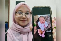 Nur Halimatussa&#039;diyah menunjukkan Alia Majidah yang ditinggalkan dalam peti pelindung bayi di Orphan Care Foundation.