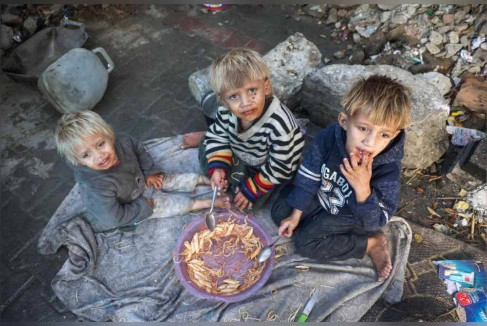 Kanak-kanak lelaki Palestin berkongsi sepinggan makanan di khemah mereka di kem pelarian Bureij di tengah Semenanjung Gaza. Foto AFP