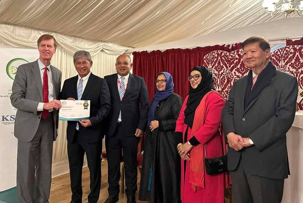 Menteri bagi Orang Kurang Upaya, Kesihatan dan Pekerjaan UK, Sir Stephen Timms (kiri) menyampaikan anugerah kepada Pengerusi Bank Muamalat, Tan Sri Tajuddin Atan (dua dari kiri) di House of Lords, Palace of Westminster, London. FOTO/ Bank Muamalat.