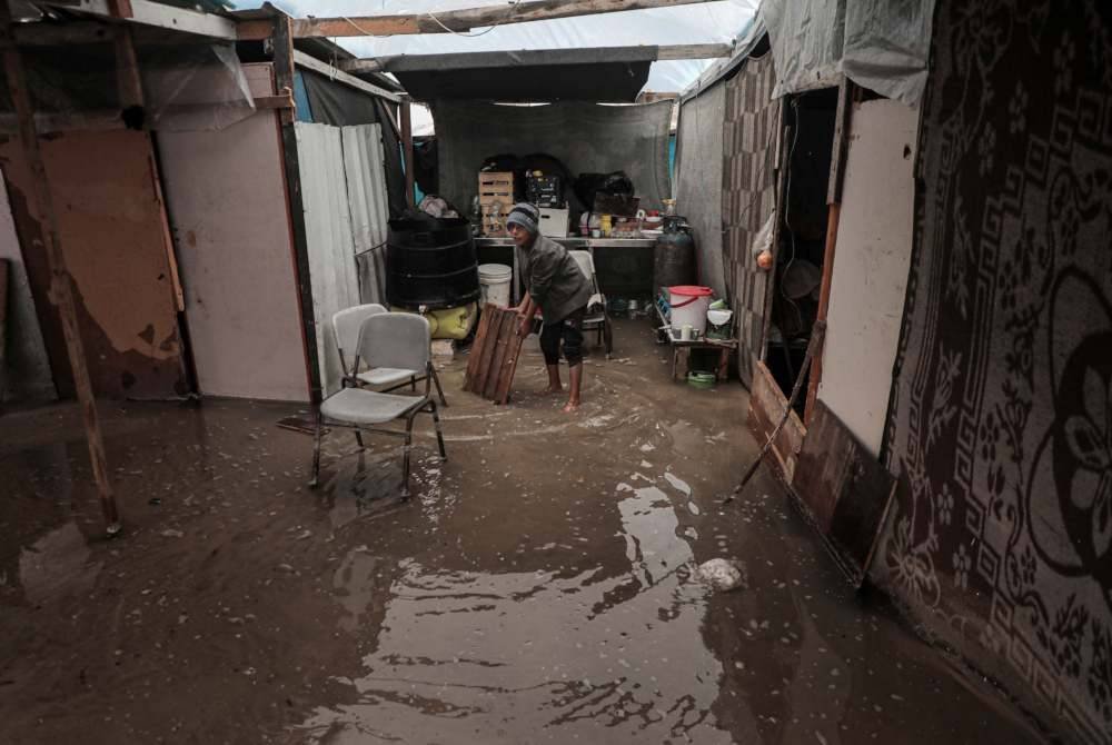 Seorang budak lelaki berada dalam khemah yang ditenggelami air selepas hujan lebat di kawasan Mawasi di Khan Younis, selatan Semenanjung Gaza. Foto Xinhua