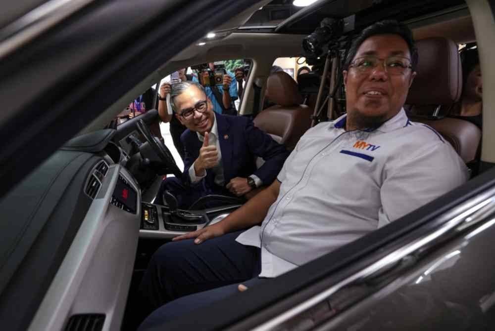 Fahmi bersama Timbalan Presiden Inovasi dan Pembangunan Perniagaan MYTV, Syaffandi Shahrom pada Majlis Pelancaran Aplikasi MYTV Mana-Mana Bagi Proton X Series di Proton DX hari ini. Foto Bernama