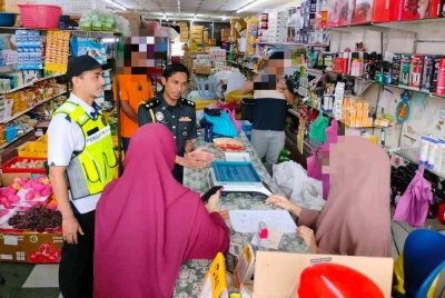 Muhammad Nizam (kiri) membuat pemeriksaan ke sebuah kedai runcit di Sungai Petani pada Rabu.