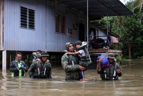 Pegawai Memerintah Batalion ke-18 Rejimen Askar Melayu Diraja (18RAMD) (Para) Kem Sri Pantai, Leftenan Kolonel Mohd Ashafiq Abd Aziz (tiga, kanan) bersama anggotanya membantu memindahkan kanak-kanak yang terperangkap dalam kediaman mereka menerusi Ops Murni di Kampung Tengkawang, hari ini. Foto Bernama