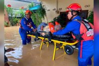 Anggota penyelamat membantu memindahkan seorang mangsa banjir selepas kediamannya dinaiki air. - Foto APM