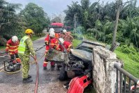 Anggota bomba membantu memadam kebakaran teksi di Kampung Lanchang, Jalan Jasin-Merlimau di sini, pada Khamis.