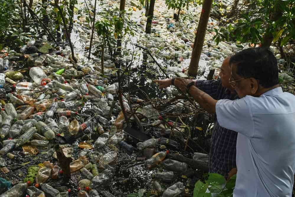 Subbarow (kanan) menunjukkan longgokan sampah terutama botol-botol plastik yang dibuang berhampiran jeti nelayan di Kampung Binjai, Bayan Lepas di sini. Foto Bernama