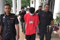 Tertuduh diiringi anggota polis ketika dibawa ke Mahkamah Balik Pulau, pada Jumaat.