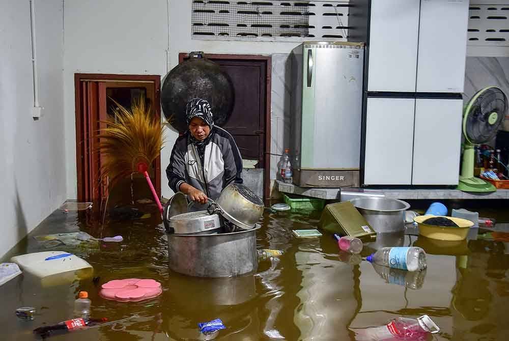 Seorang penduduk melihat barang-barang yang terapung di dalam rumahnya berikutan hujan lebat di wilayah selatan Narathiwat, Thailand. Foto AFP