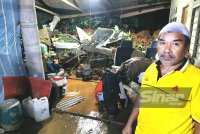 Mohd Fauzi menunjukkan bahagian rumah yang ditimpa tanah runtuh dalam kejadian pada petang Jumaat di Kampung Baru Ajil, Hulu Terengganu.