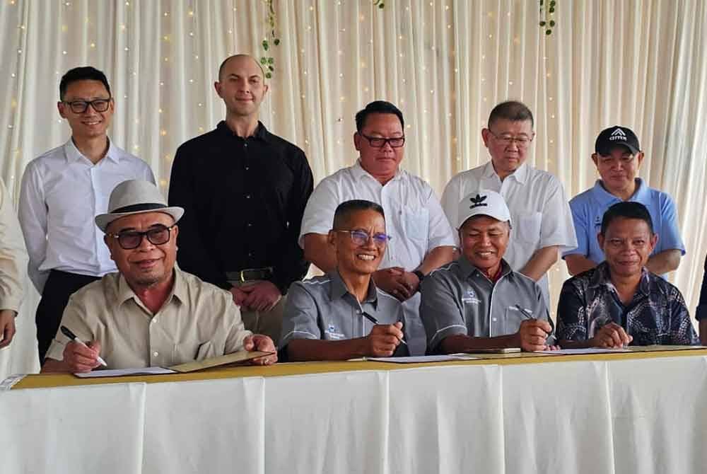 Yahya (duduk: kiri) menandatangani perjanjian sewaan tanah bersama wakil penduduk kampung di Tandek dan disaksikan Hendrus (tengah) di Dewan Tandek, Kota Marudu.