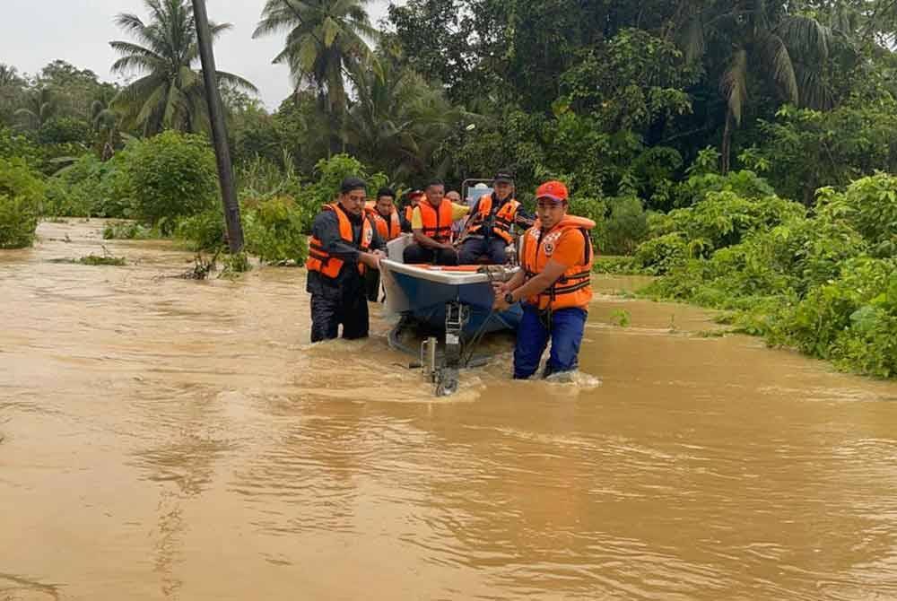 Anggota APM daerah Raub membantu memindahkan mangsa banjir dari kawasan terjejas ke PPS yang dibuka di daerah itu pada Ahad.