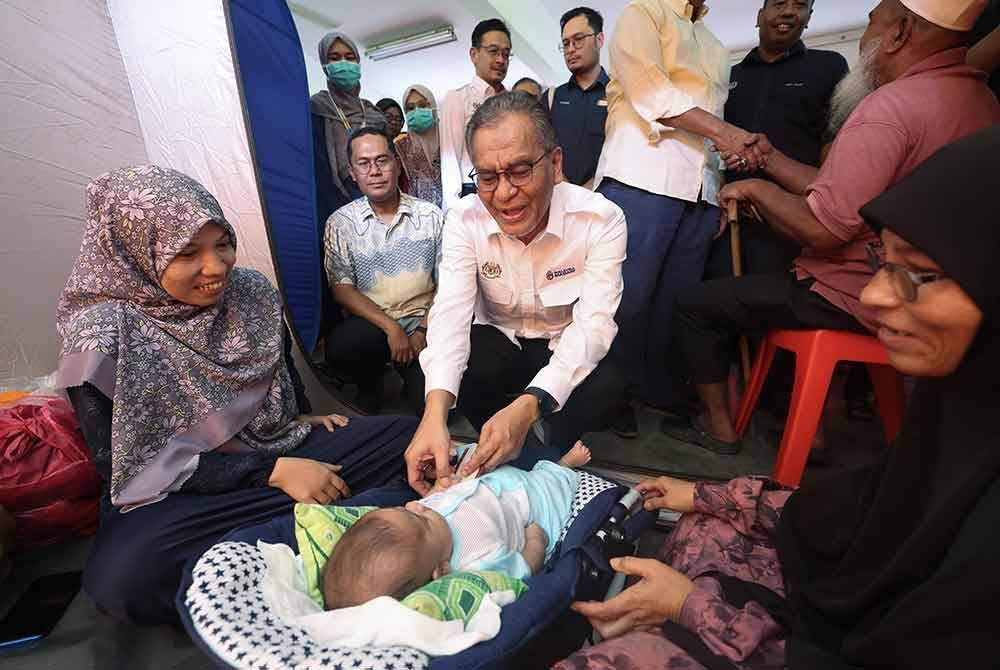 Dr Dzulkefly menyantuni mangsa banjir ketika mengadakan lawatan ke Pusat Pemindahan Sementara (PSS) di Sekolah Menengah Kebangsaan Kepala Batas hari ini. Foto Bernama