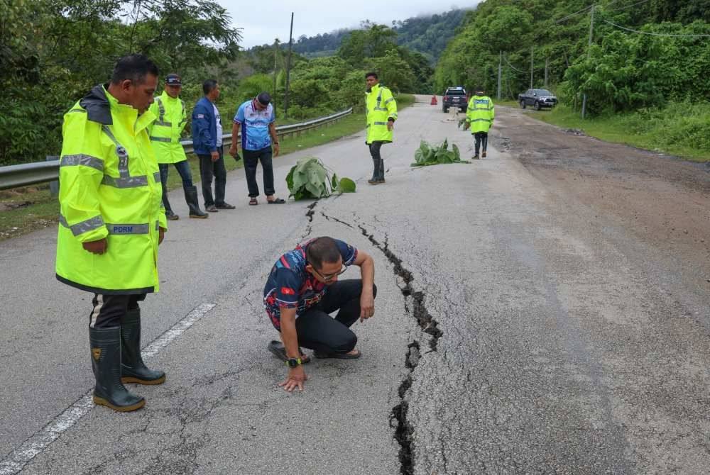 Mohd Azmawi Fikri melihat jalan merekah dan mendap sepanjang 110 meter yang dikesan berlaku di Jalan D241 pada laluan masuk ke Kampung Jerek ketika tinjauan di sini. Foto Bernama