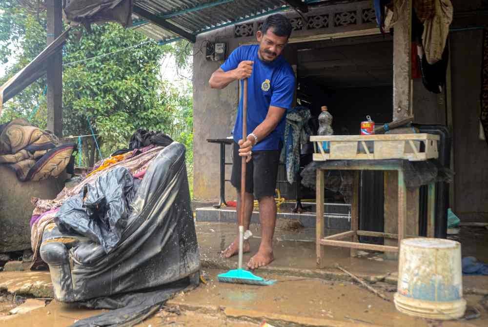 Penduduk Azree Awang, 44, membersihkan lumpur di kediamannya akibat banjir beberapa hari lalu ketika tinjauan di Kampung Padang Kijang hari ini. Foto Bernama