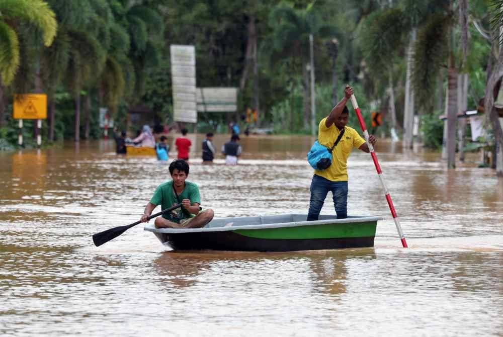 Penduduk setempat terpaksa menggunakan sampan sebagai pengangkutan untuk berulang alik dari PPS ke rumah mereka selepas jalan utama terputus akibat banjir yang melanda daerah Hulu Terengganu. Foto Bernama