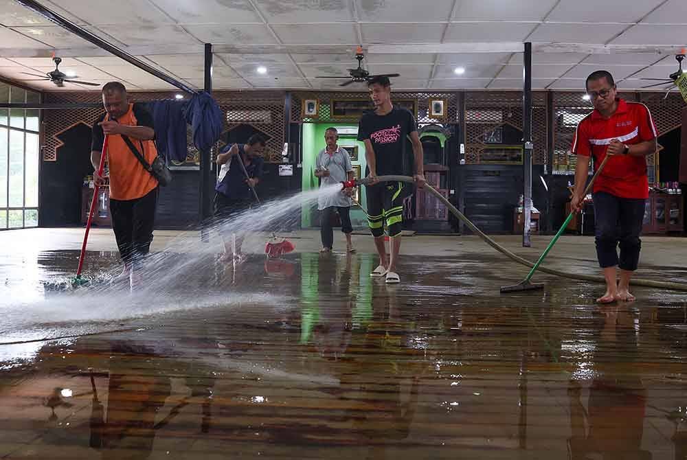 Kira-kira 30 ahli qariah Masjid Pasir Simpul, Hulu Terengganu berganding bahu membersihkan masjid kampung itu yang turut terkesan banjir. Foto Bernama