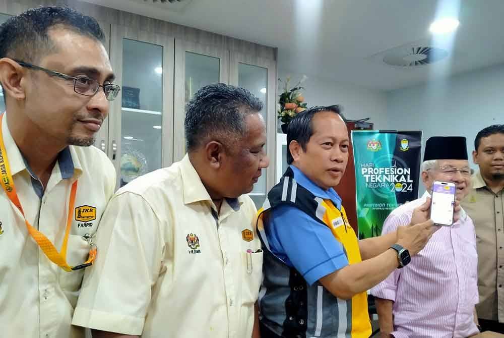 Ahmad (tengah) menunjukkan portal bencana alam JKR ketika sidang akhbar selepas mengadakan lawatan rasmi ke Pejabat JKR Perak di Ipoh pada Selasa.