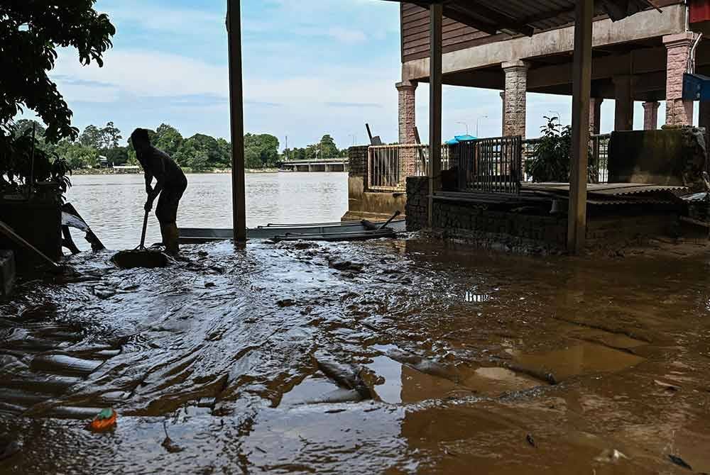 Penduduk, Mohd Hazwan Yahaya, 34, membersihkan lumpur di kediamannya setelah banjir mulai surut ketika tinjauan di Kampung Pulau Rusa, Kuala Terengganu pada Selasa. Foto Bernama