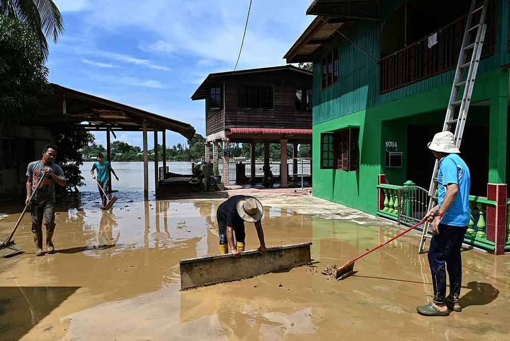 Penduduk membersihkan lumpur di kediaman mereka setelah banjir mulai surut ketika tinjauan di Kampung Pulau Rusa, Kuala Terengganu hari ini. - Foto: Bernama