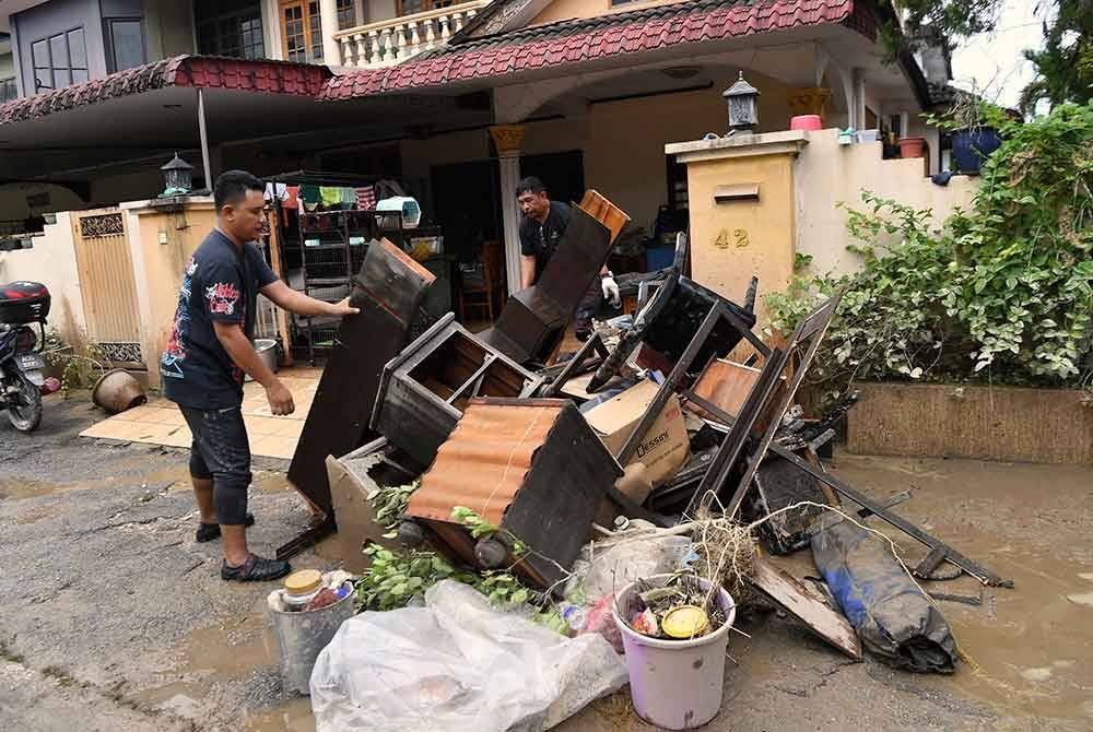 Penduduk membersihkan kediaman masing-masing dengan membuang barang-barang yang rosak akibat banjir. Gambar hiasan Bernama