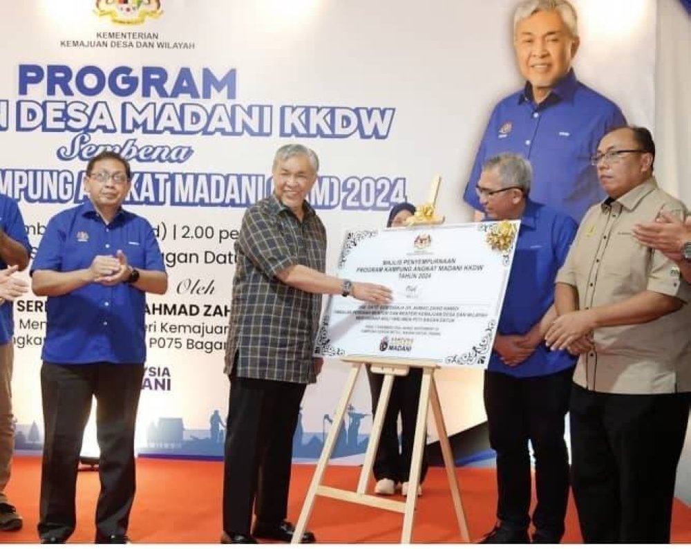 Ahmad Zahid (dua dari kiri) menandatangani plak Majlis Penyempurnaan Program Kampung Angkat Madani KKDW 2024 pada Program Tautan Desa Madani KKDW Sempena Program KAM 2024 di SK Sungai Betul di sini, Ahad.