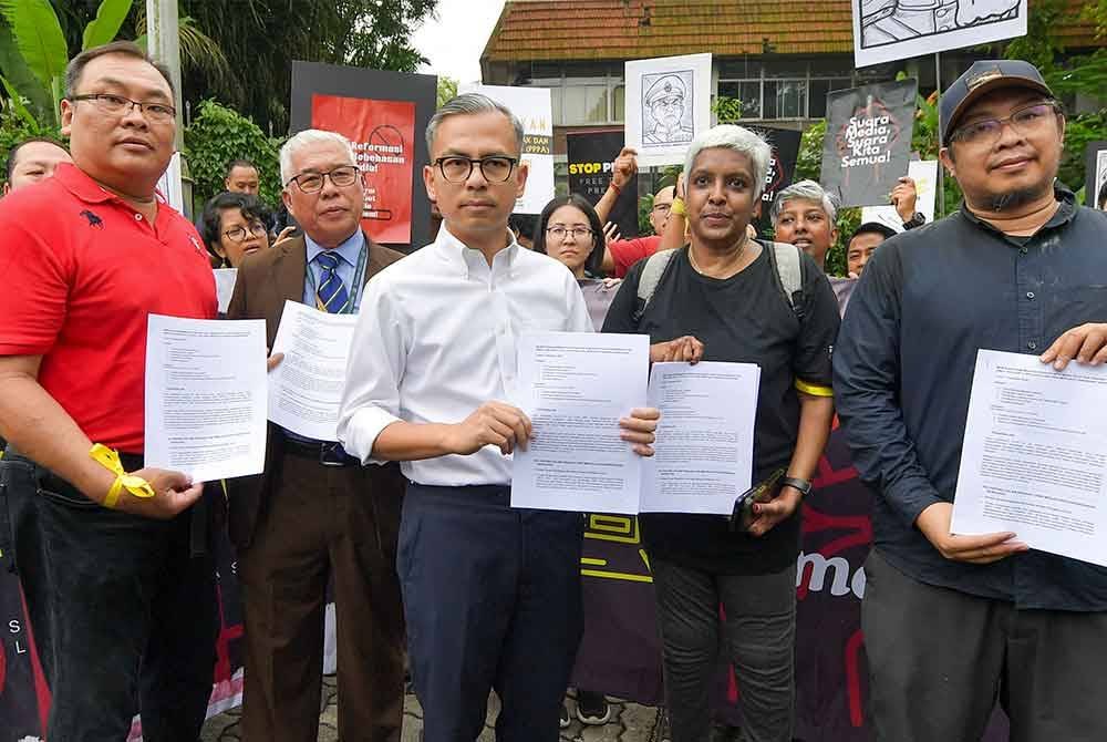 Fahmi Fadzil (tiga dari kiri) menerima memorandum daripada Sekretariat Fourth for the Fourth (404), yang diwakili oleh Radzi Razak (kanan) di perkarangan Parlimen hari ini. - Foto: Bernama