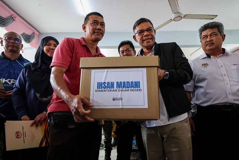 Menteri Dalam Negeri, Datuk Seri Saifuddin Nasution Ismail (dua, kanan) menyampaikan sumbangan kepada mangsa banjir semasa melakukan lawatan di Pusat Pemindahan Sementara (PPS) Sekolah Kebangsaan Bukit Tinggi, pada Rabu. Foto Bernama