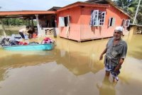 Zakaria (kanan) meninjau rumahnya yang dinaiki air di Kampung Nyatoh di Setiu pada Rabu.