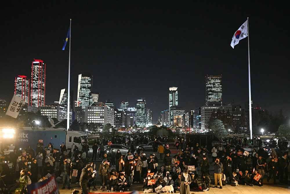 Orang ramai berkumpul di pekarangan Perhimpunan Kebangsaan di Seoul pada 4 Disember. Foto AFP