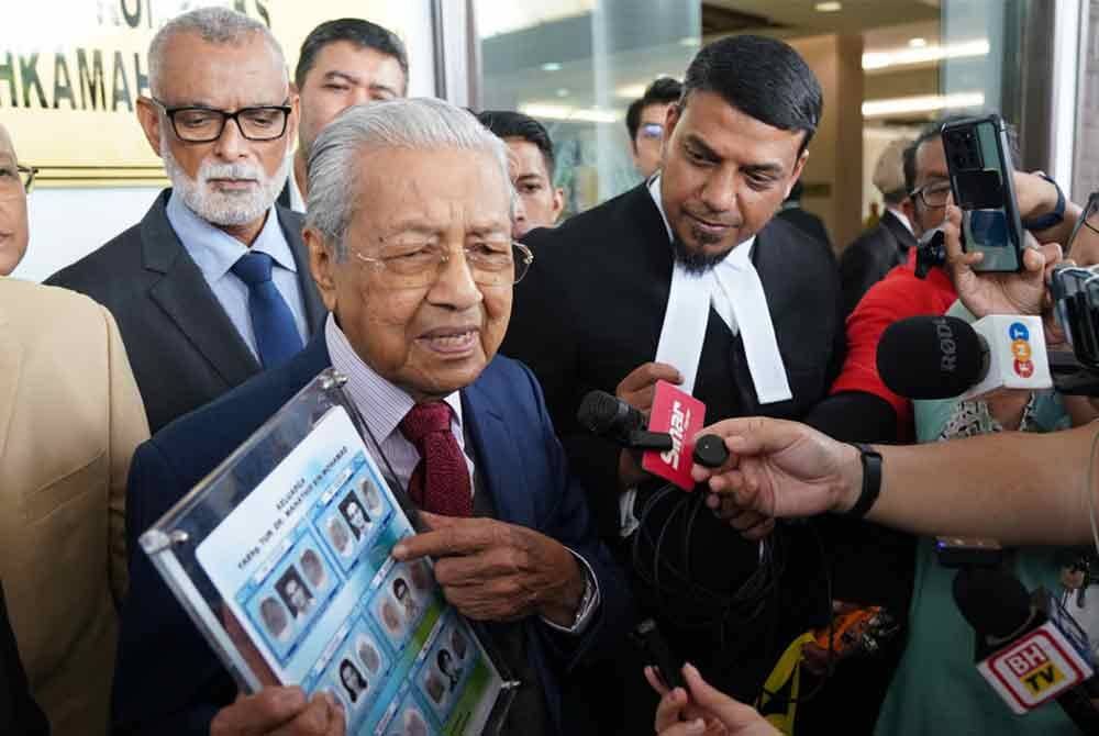 Dr Mahathir menunjukkan salinan kad pengenalan lama miliknya, sebagai bukti di Mahkamah Tinggi pada Khamis, bagi mengesahkan namanya bukan `Mahathir anak lelaki Iskandar Kutty&#039;.