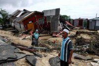 Penduduk setempat melintasi kawasan yang musnah akibat dilanda banjir ketika tinjauan di Kampung Baru Nelayan. Foto Bernama