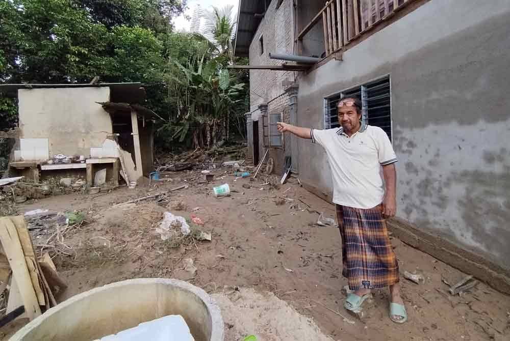 Raja Kamarudin menunjukkan lokasi rumah pusaka yang dihuni tujuh sekeluarga dihanyutkan banjir pada Disember 2022.