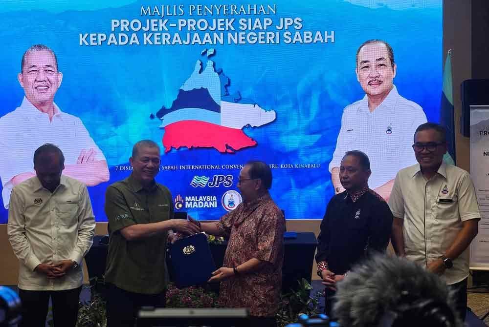 Fadillah (dua dari kiri) menyerahkan dokumen projek siap kepada Timbalan Ketua Menteri Datuk Seri Dr Jeffrey Kitingan (tiga dari kanan) pada majlis serahan projek siap di SICC, Kota Kinabalu.