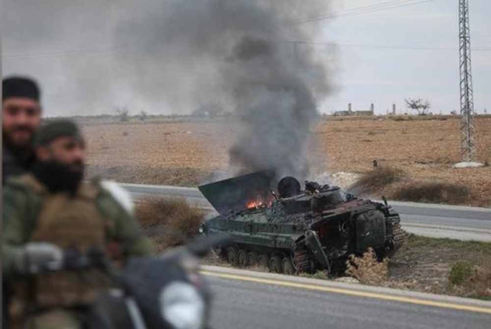 Tentera pembangkang Syria memandu melepasi kenderaan perisai kerajaan yang terbakar di selatan Hama, Syria pada Sabtu. Foto AP