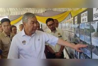 Ahmad Zahid melihat pelan perancangan pembinaan jalan semasa Majlis Penyerahan Projek Jalan Luar Bandar di Jalan Peket 100, Simpang Lima, Sungai Besar pada Ahad.