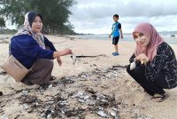 Wan Zurafifah (kanan) menunjukkan ikan kecil yang terdampar di Pantai Bari, Setiu.