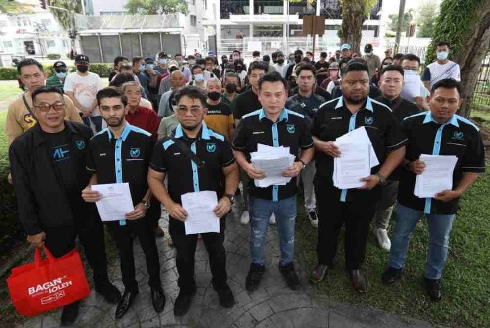 Hishamuddin (tiga dari kiri) memegang kertas aduan daripada mangsa yang mendakwa ditipu oleh syarikat pelaburan tersebut.