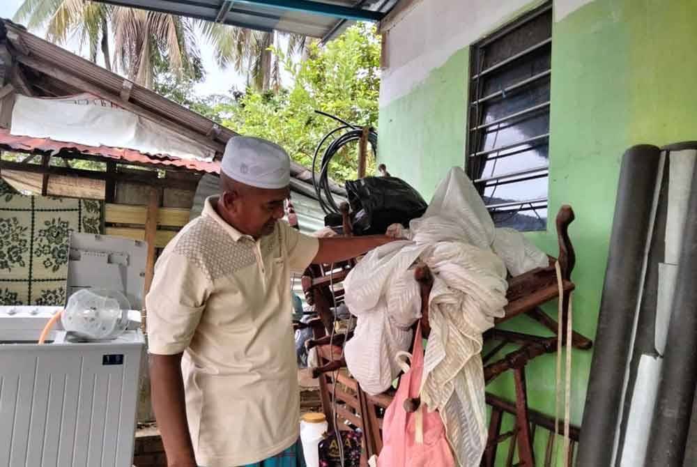 Shaari menunjukkan langsir rumah yang masih belum dicuci kerana banyak perkakas yang perlu dikemaskan.